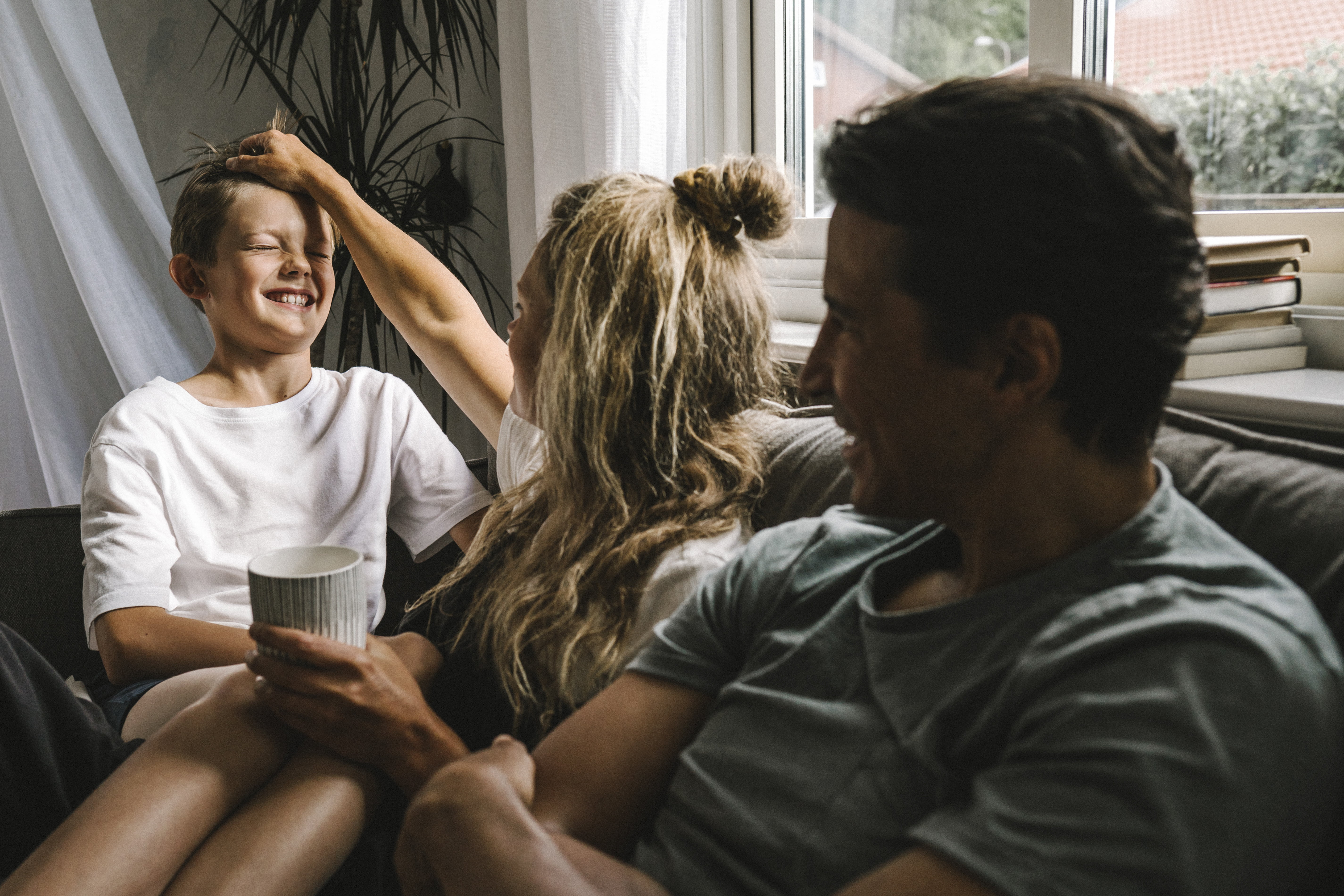 Gutt som sitter og tøyser med foreldre i sofa