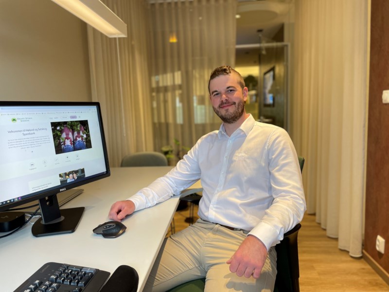 En mann som smiler mens han sitter foran en pc-skjerm